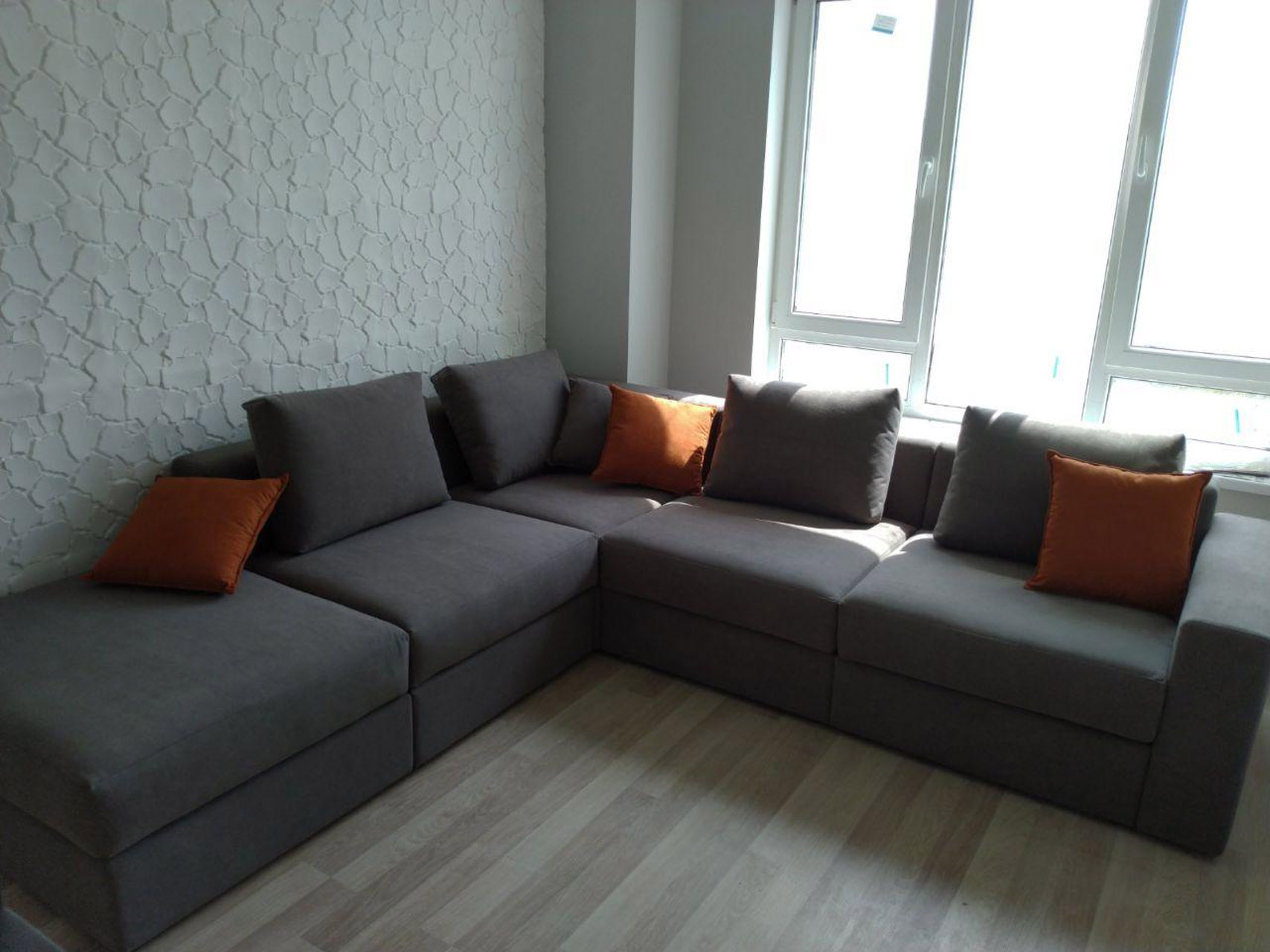 Серый диван с оранжевыми подушками